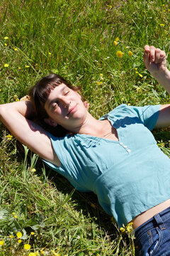 Woman relaxing on sunny meadow grass with wildflowers