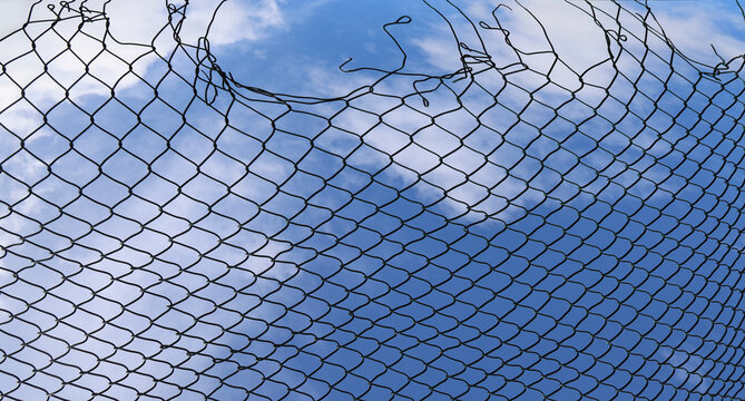 Opening in metallic net fence. isolated on blue sky background. Challenge. uncertainty. breakthrough concept. freedom concept. Chainlink, wire netting, wire-mesh.