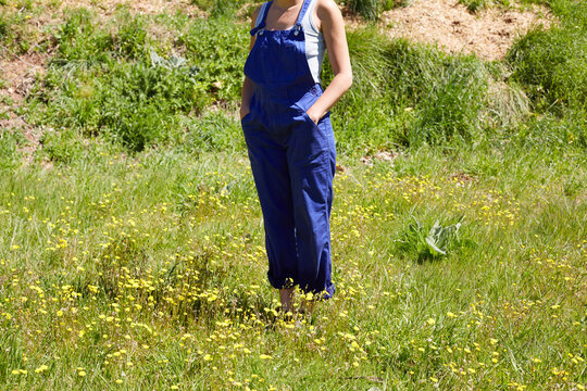 Woman in blue overalls standing in rural meadow