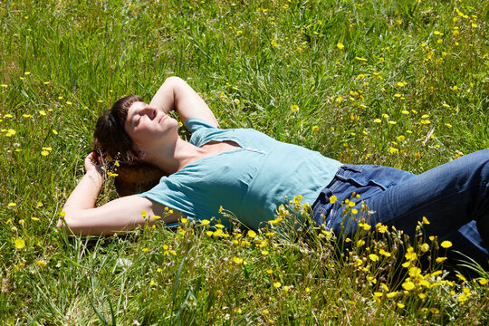 Woman resting in sunny wildflower meadow on summer day