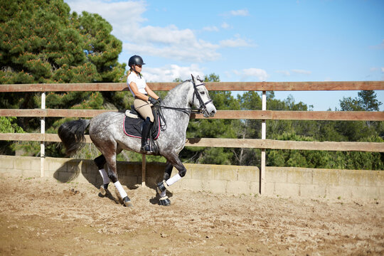 Woman riding horse in equestrian arena with helmet
