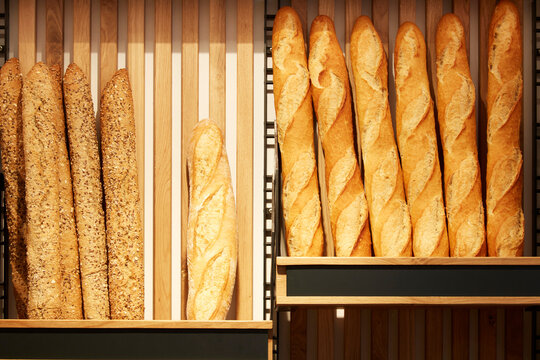 Assorted baguette and seeded bread on wooden rack