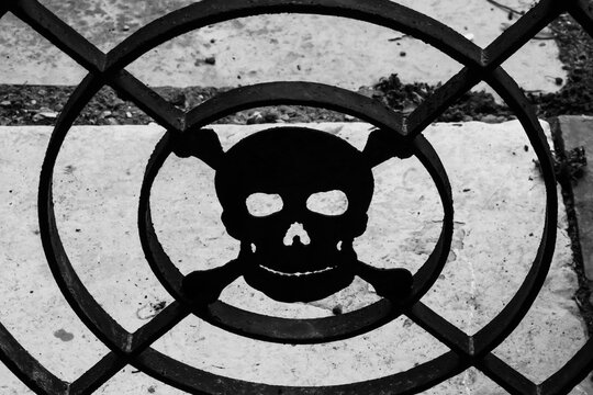 La sagoma in ferro battuto di un teschio, simbolo della morte, su una cancellata in un cimitero