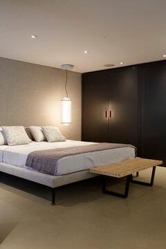 Minimal bedroom interior with pendant light and dark wardrobe