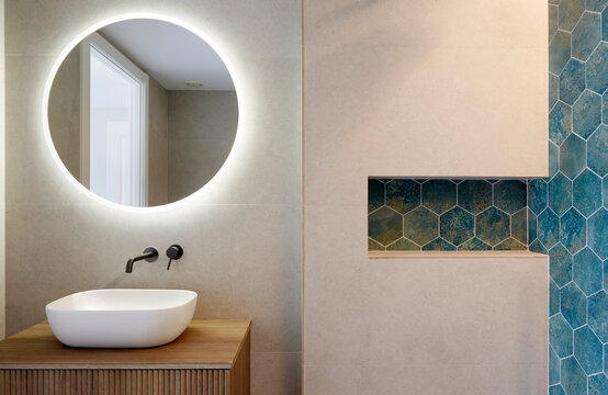 Modern bathroom with round mirror and blue tile wall