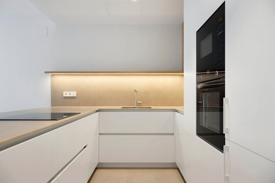 Modern white kitchen interior with built in oven and sink