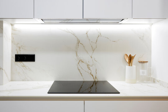 Modern white marble kitchen backsplash with black cooktop