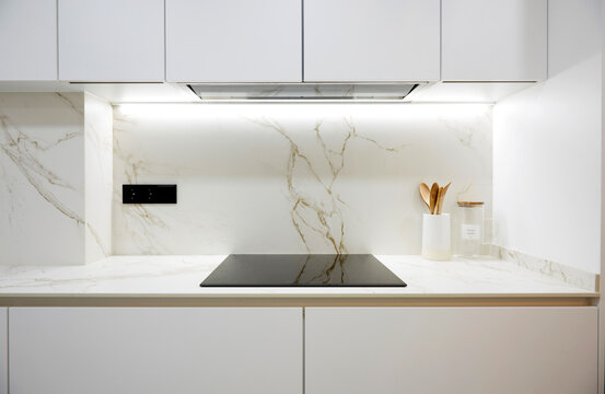 Minimal white kitchen with marble backsplash and cooktop