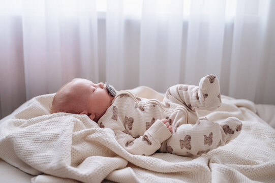 One month old baby boy lying on comfortable white sheet