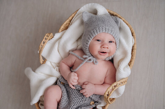 Smiling infant in knitted outfit sits in basket
