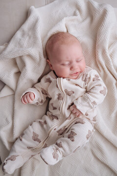 Peaceful baby boy lying on soft white sheet resting