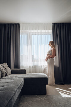 Pregnant woman basking in morning light by a window