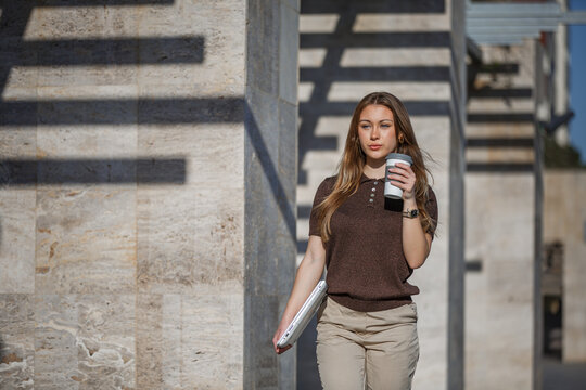Woman working in a public park holding a coffee cup