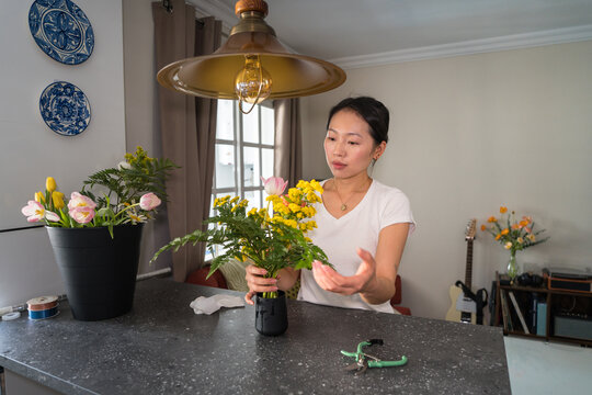 Woman arranging fresh flowers at home as creative hobby