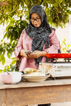 Muslim Indonesian woman preparing traditional food at stall