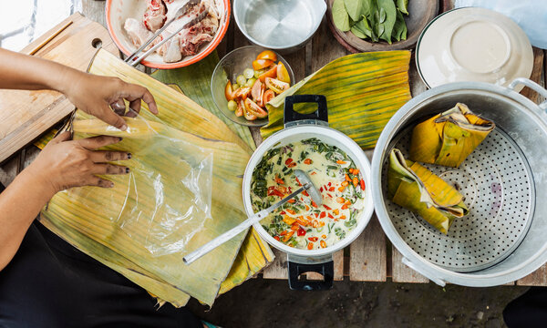 Muslim woman preparing traditional Indonesian food on table