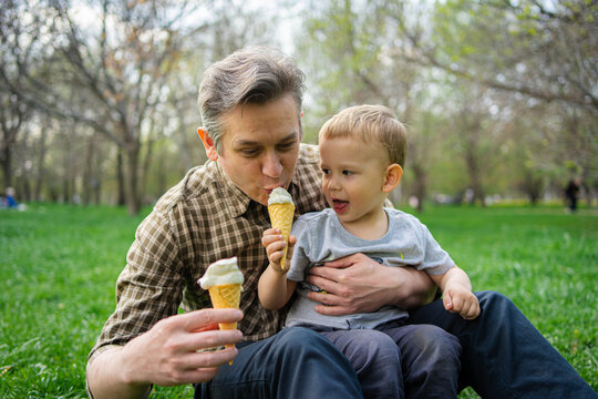 Father and son sharing ice cream during spring park