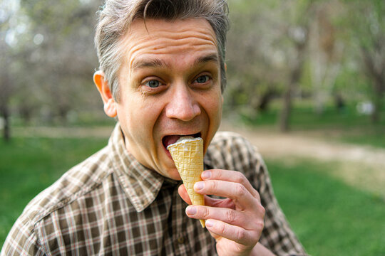 Man enjoying ice cream cone outdoors in a city park