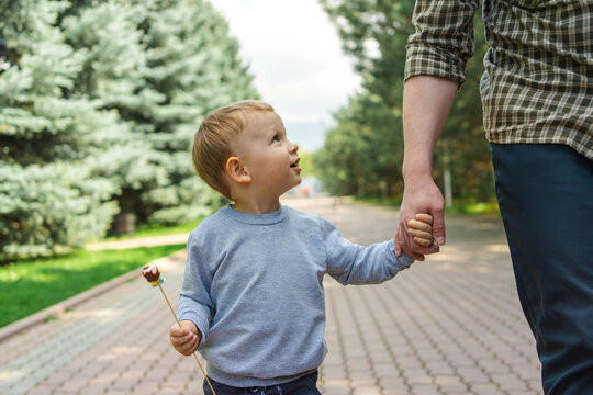 Father and son holding hands on a spring park walk