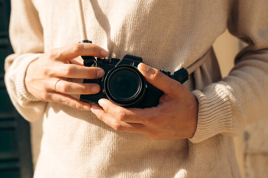 Photographer man holding vintage camera in warm sunlight