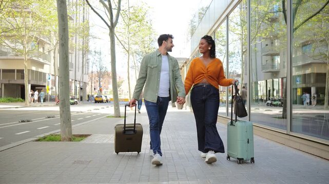 Joyful couple walking side by side while carrying their suitcases together, sharing smiles and laughter during their travel adventure on a beautiful day full of possibilities and excitement.