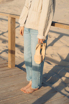 Woman on coast holding sandals in Aveiro, Portugal