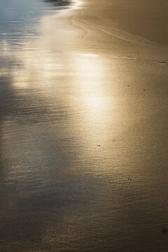 Tranquil beach with golden sand reflections