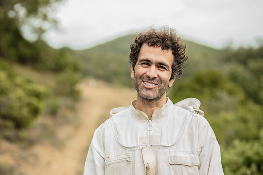 Beekeeper smiling in protective suit in nature