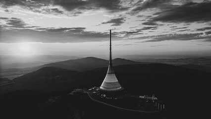 Jested Mountain Hotel stands majestically above Liberec, showcasing modern architecture against a backdrop of a colorful sunset. The evening sky casts a beautiful glow over the mountain landscape. © pyty