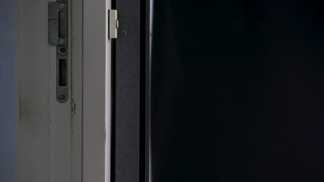 Close up of a man in dark jacket locking and closing his modern apartment door on a residential gallery before leaving home
