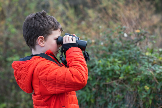 Young explorer birdwatching with binoculars in nature