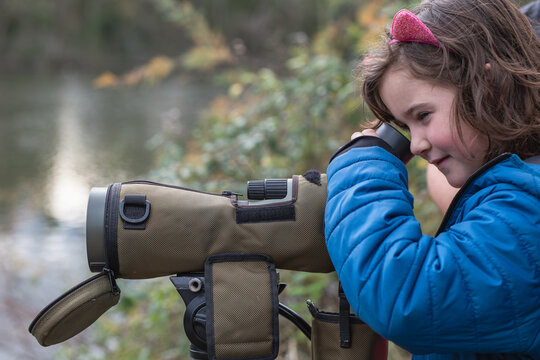 Child birdwatching with spotting scope in nature