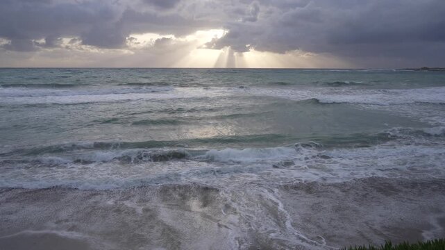 View of sunset breaking through clouds and sea towards Paphos Castle and Harbour, Paphos, Cyprus