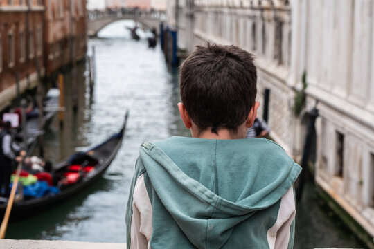 Child watching gondola on Venice canal from bridge view