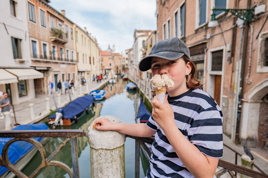 Teen girl eating gelato on a Venice canal bridge