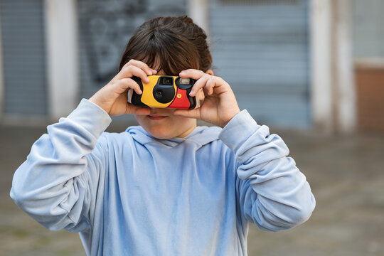 Child using disposable camera outdoors, close up portrait