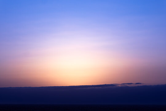 Pastel sunrise above cloud horizon with soft gradient sky