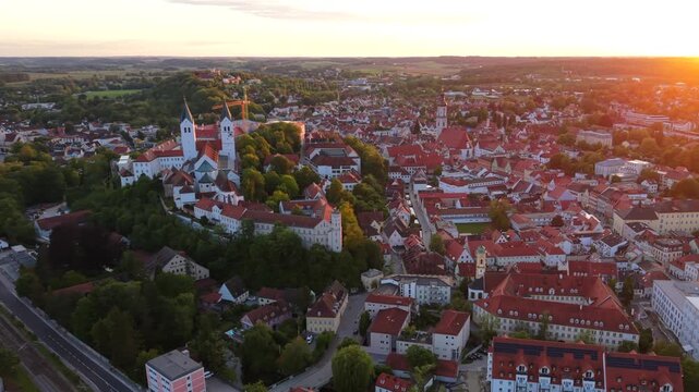 Freisings historic center in Upper Bavaria, Germany, appears from above with the cathedral hill, St. George Church, and the residence tower illuminated by a golden summer sunset.