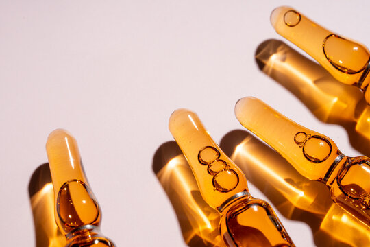 Amber glass beauty ampule with cosmetic serum on white
