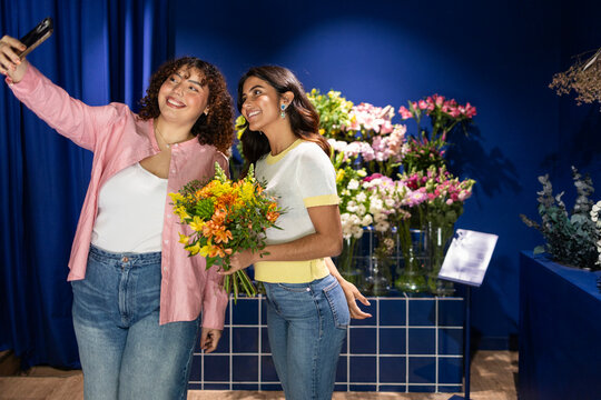 Two friends in a flower shop capturing joy in blue setting
