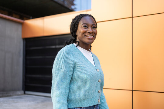 Smiling African woman standing outdoors by modern wall