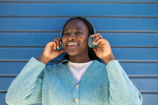 Joyful African woman listening to music on headphones outdoors