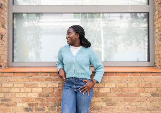 Smiling African woman leaning on brick wall outdoors