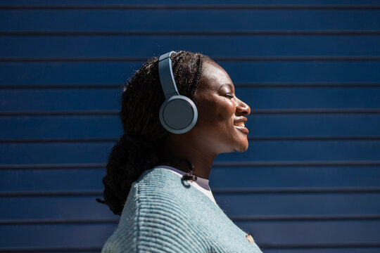 Young African woman listening to music on headphones