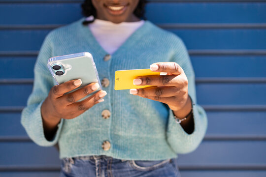 African woman using smartphone with credit card for payment