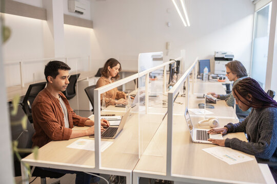 Coworking team working at shared office desks with screens