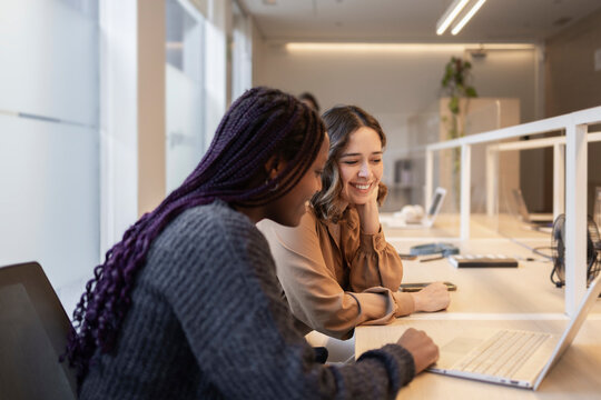 Coworking team collaborating at office desk with laptop