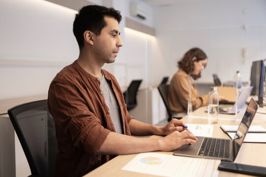 Focused coworkers working on laptops in modern office