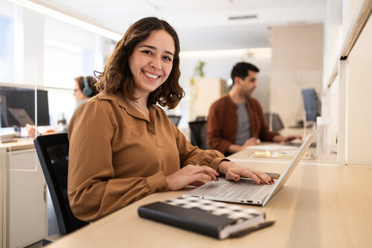 Smiling coworker working on laptop in modern shared office