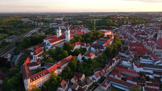 Freising, Bavaria, Germany, seen from a drone, reveals the cathedral hill with Dom St. Maria und St. Korbinian, St. George Church, and historic rooftops glowing in the summer sunset.